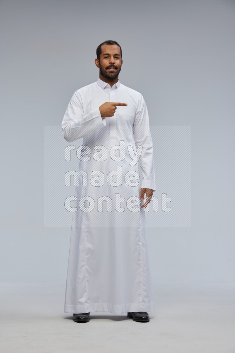 Saudi man Wearing Thob standing interacting with the camera on Gray background