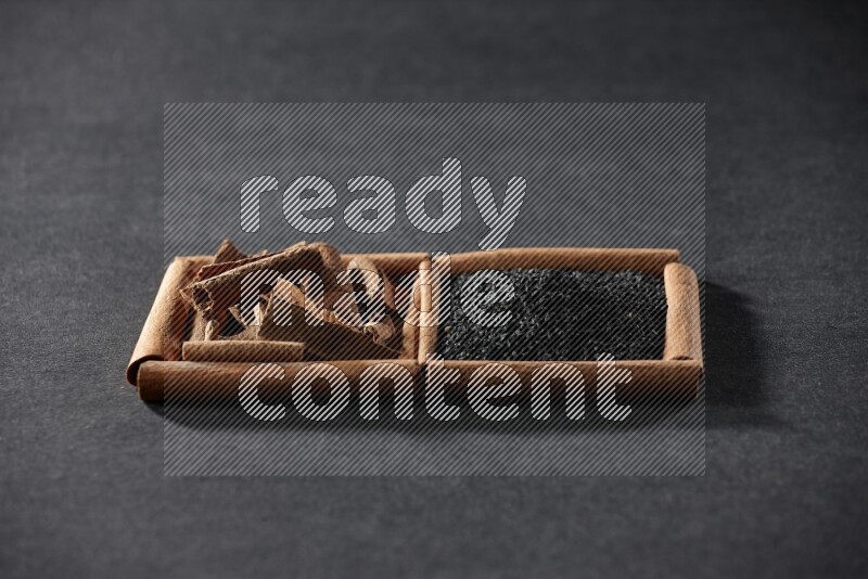 2 squares of cinnamon sticks full of black seeds and cinnamon on black flooring