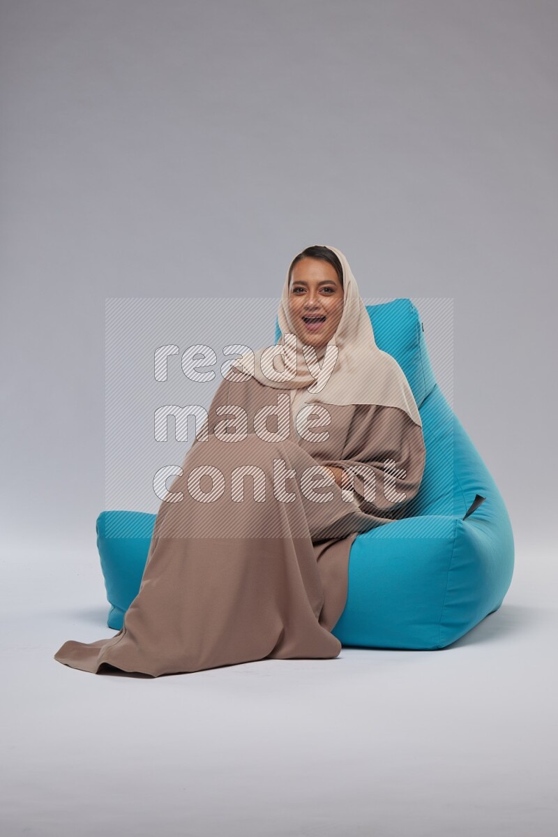 A woman sitting on a blue beanbag and interacting with the camera
