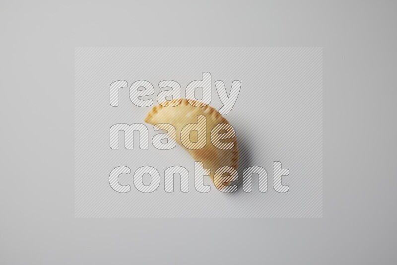 One fried sambosa from a top angle on a white background
