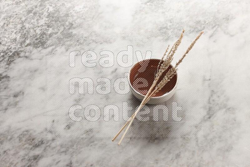 Wheat stalks on brown pottery bowl on grey marble background