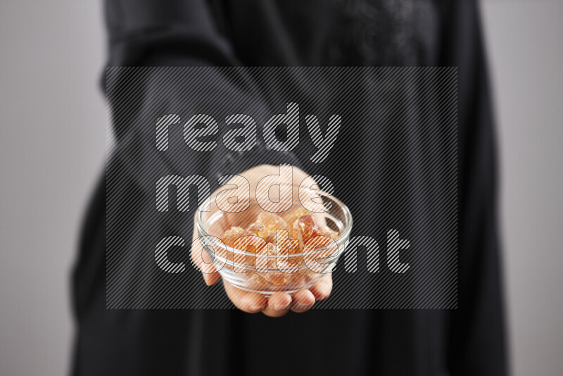 Woman in abaya holding different kinds of spices in different positions