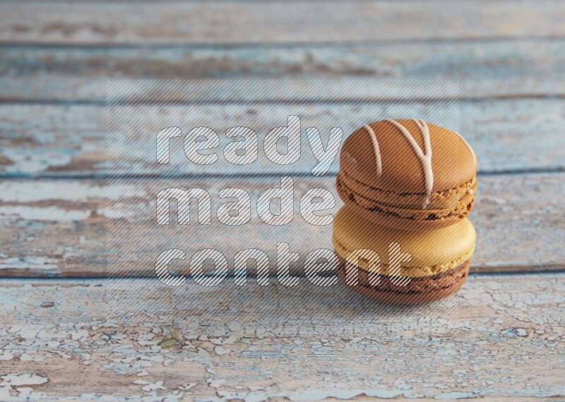 45º Shot of of two assorted Brown Irish Cream, and Yellow, and Brown Chai Latte macarons  on light blue background