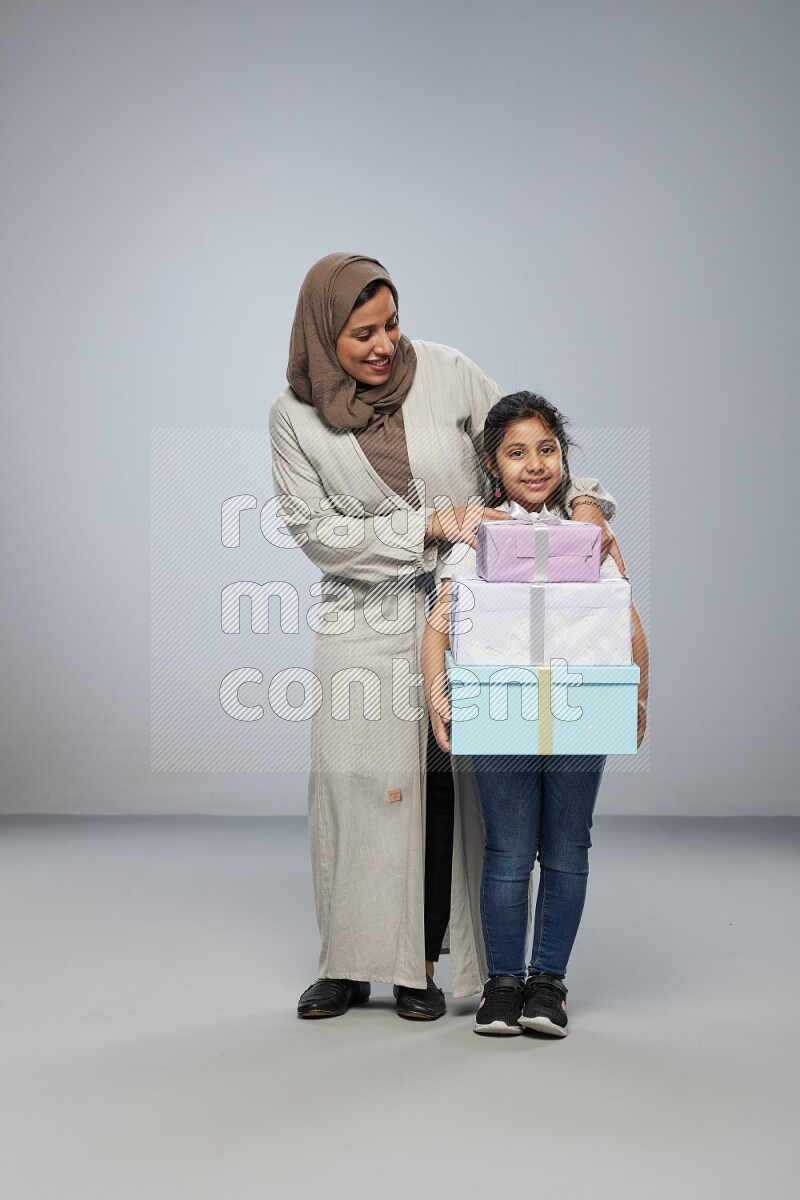 A girl giving a gift to her mother on gray background