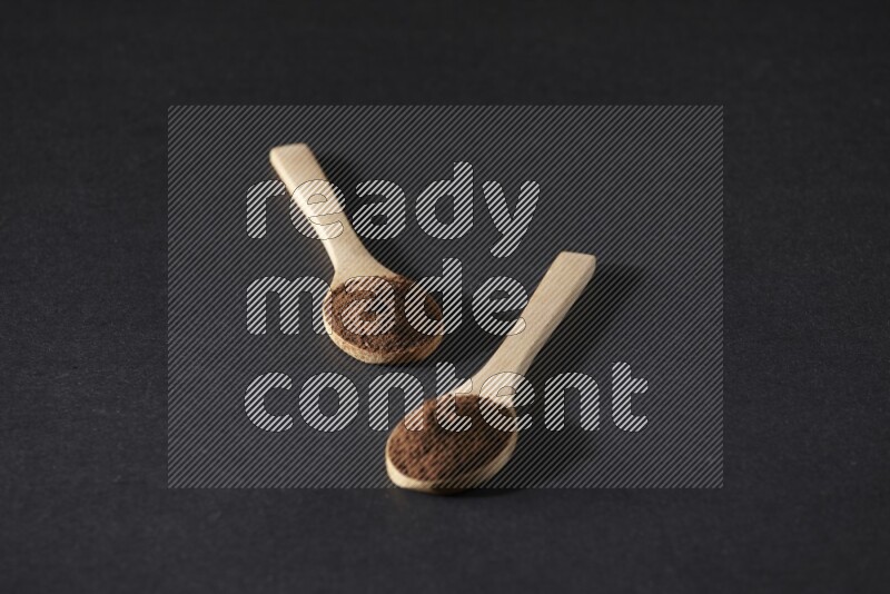 ملعقتان خشبيتان ممتلئتان ببودرة القرنفل على خلفية سوداء