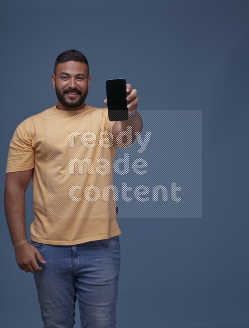 A man Showing His Smart Phone on Blue Background wearing Orange T-shirt
