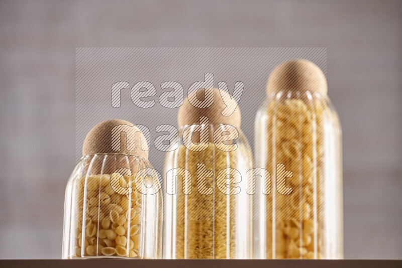 Raw pasta in glass jars on beige background