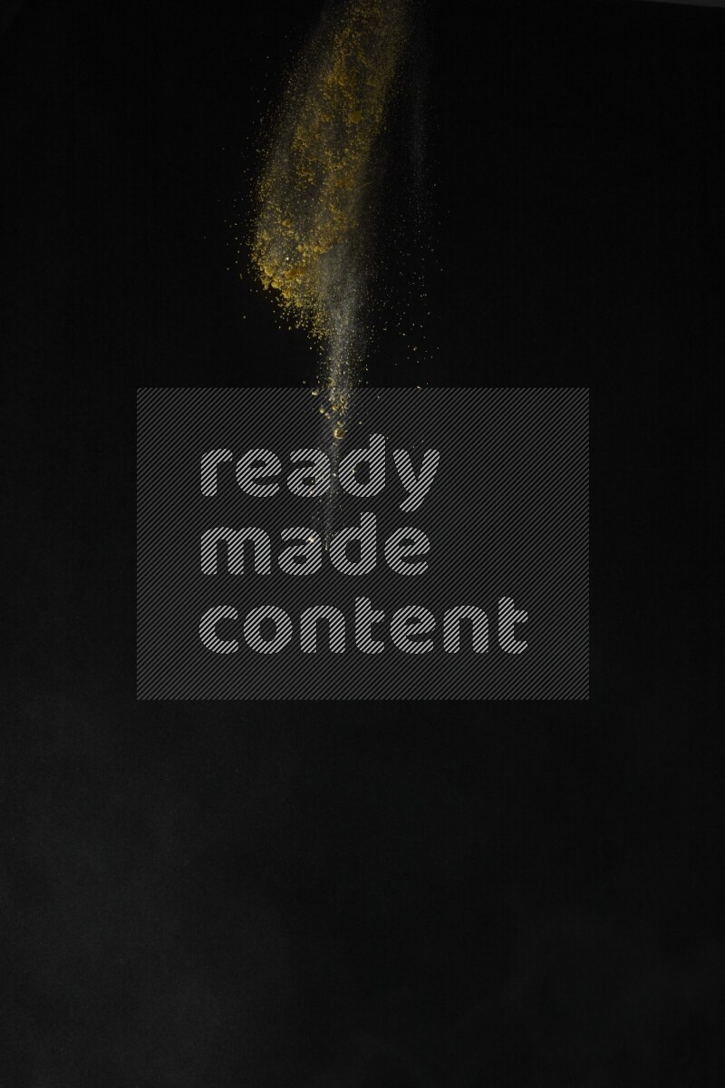 A side view of yellow powder explosion on black background