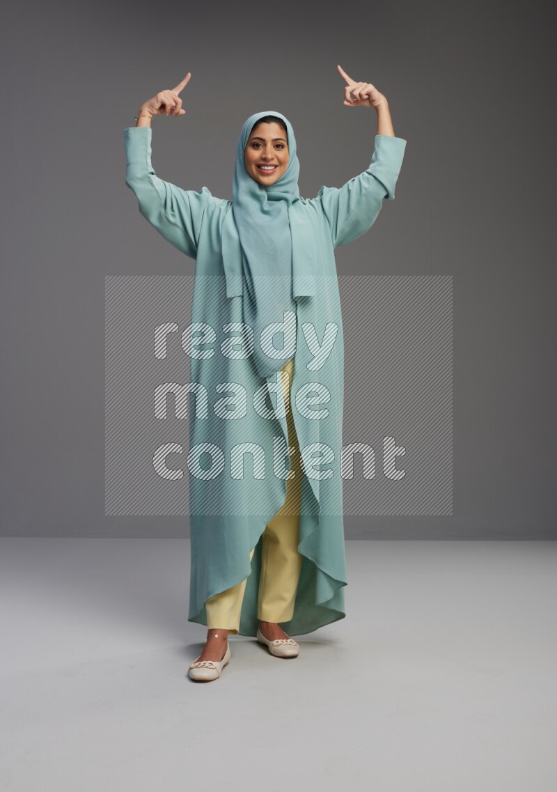 Saudi Woman wearing Abaya standing interacting with the camera on Gray background