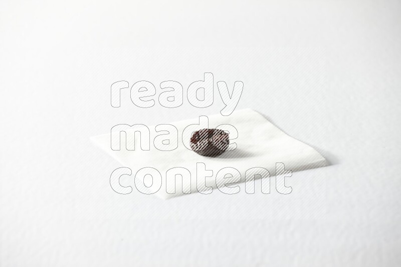 A dried plum on a piece of paper on a white background in different angles