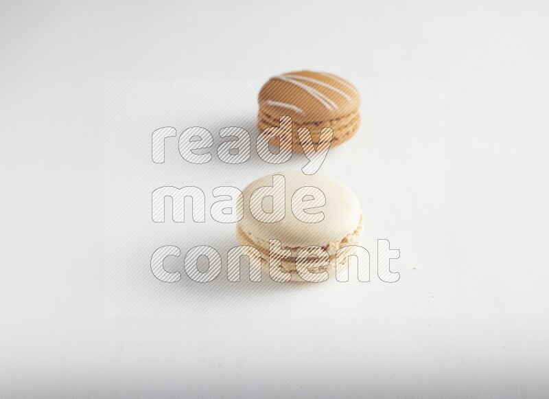 45º Shot of of two assorted Brown Irish Cream, and White Caramel fleur de sel macarons on white background