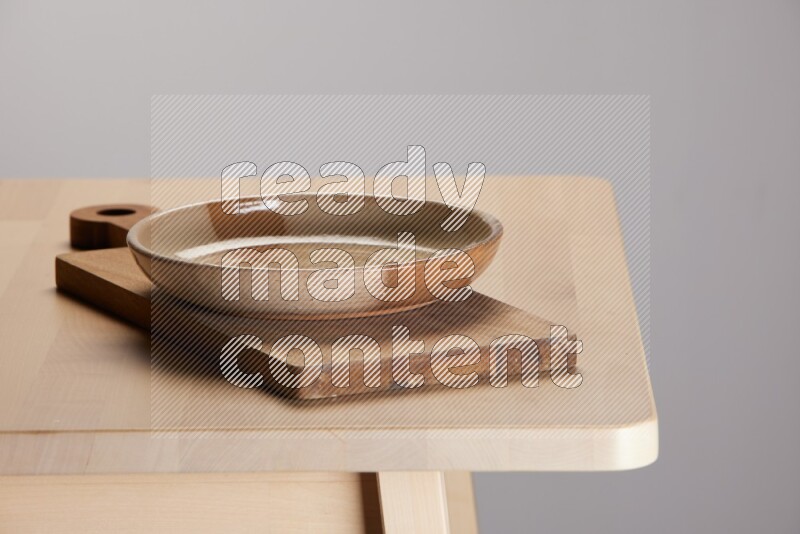 multi-colored pottery Plate placed on a  wooden rectangular cutting board on the edge of wooden table
