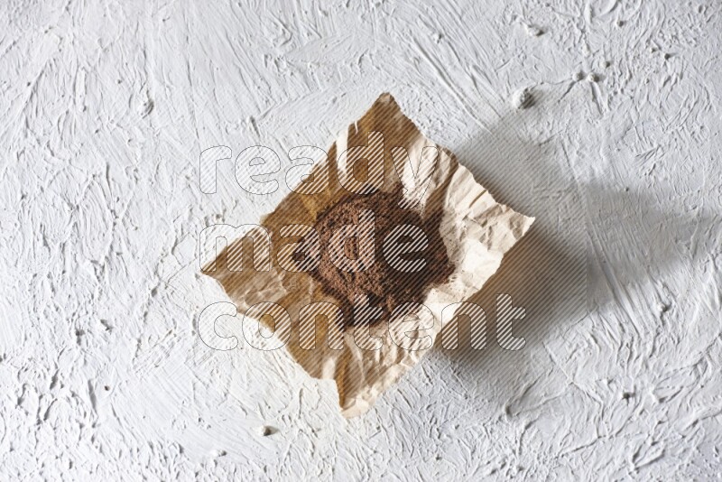 Cloves powder on crumpled piece of paper on a textured white flooring