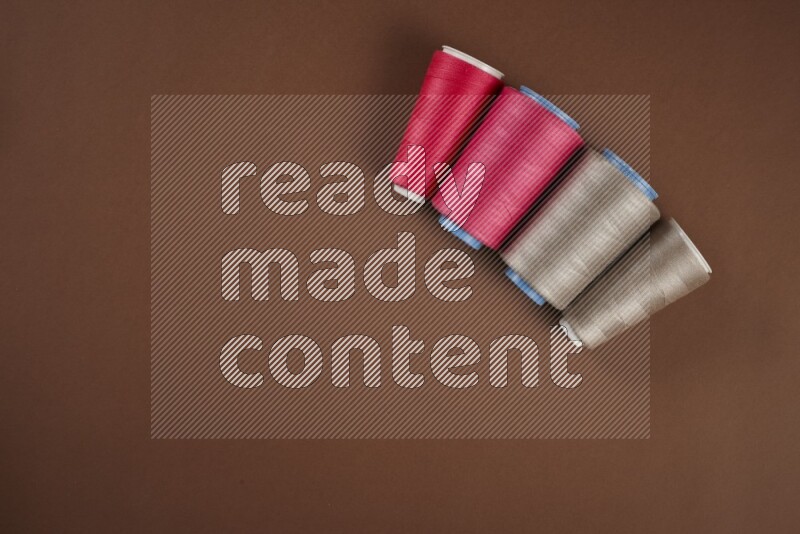 A pink collection of sewing and tailoring tools arranged on a brown background