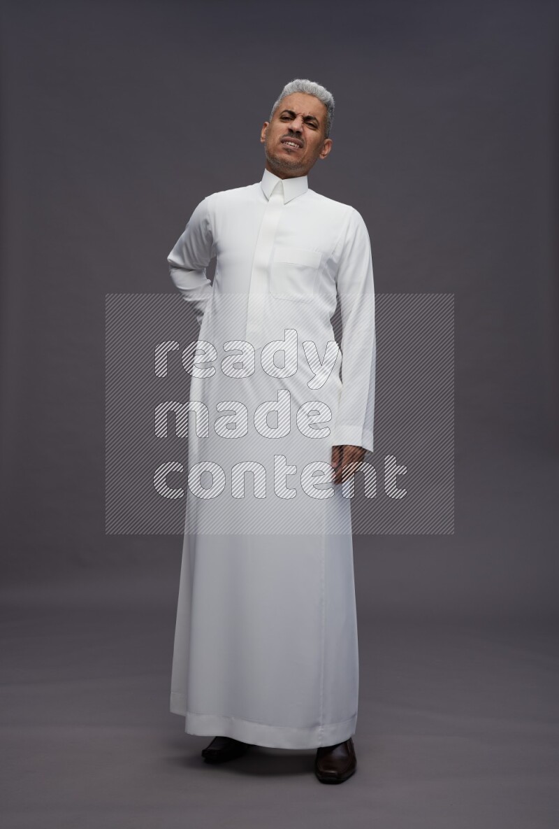 Saudi man wearing thob standing interacting with the camera on gray background