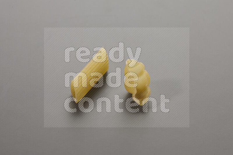 Penne pasta with other types of pasta on grey background