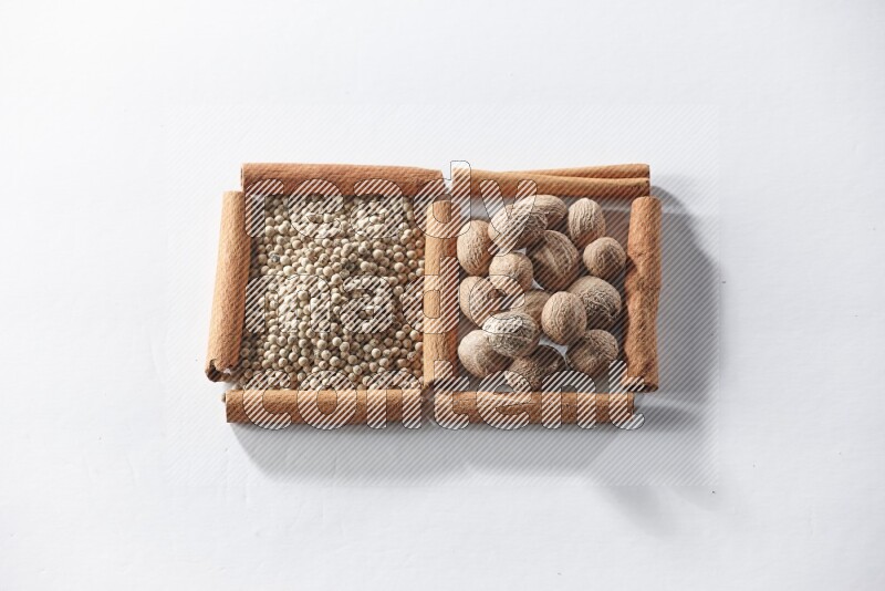 2 squares of cinnamon sticks full of white pepper and nutmegs on white flooring