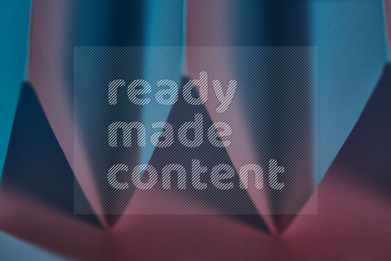 صورة مجردة مقربة تظهر طيات ورقية هندسية حادة بتدرجات اللون الأزرق والأحمر