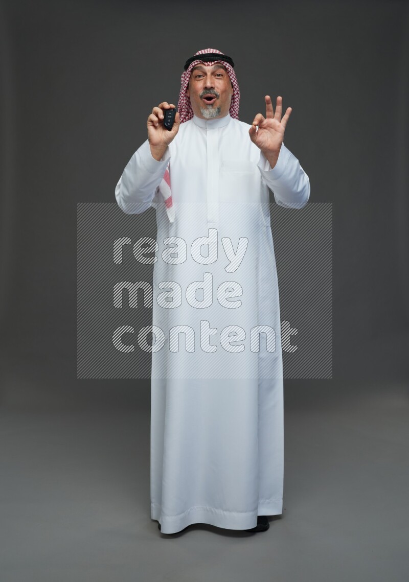 Saudi man with shomag Standing holding car key on gray background