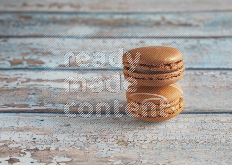 45º Shot of of two assorted Brown Irish Cream, and Brown Coffee macarons on light blue background
