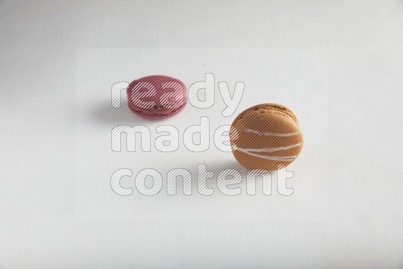 45º Shot of of two assorted Brown Irish Cream, and Red Cherry macarons on white background
