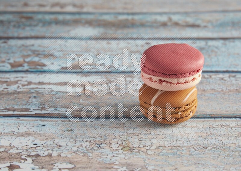 45º Shot of of two assorted Brown Irish Cream, and Pink Litchi Raspberry macarons on light blue background