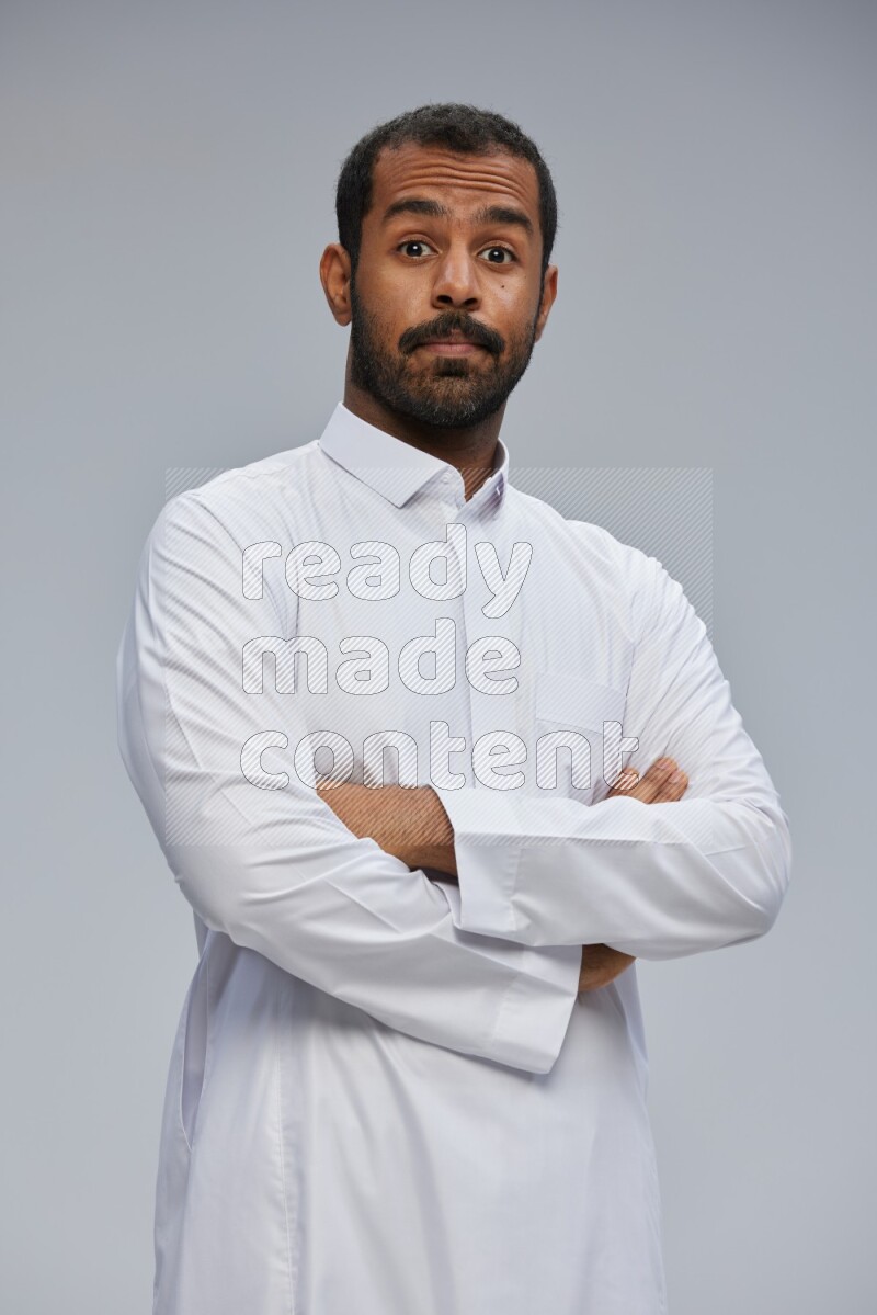 Saudi man wearing Thob standing with crossed arms on Gray background