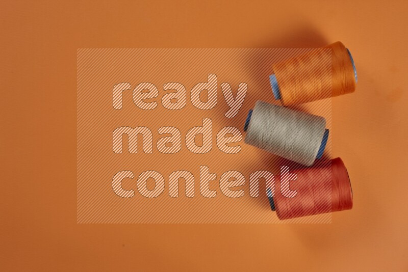 مجموعة من أدوات الخياطة والتفصيل بنية اللون على خلفية برتقالية