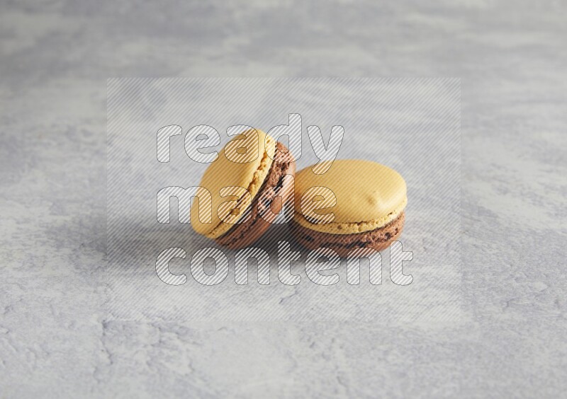 45º Shot of two Yellow and Brown Chai Latte macarons r on white  marble background