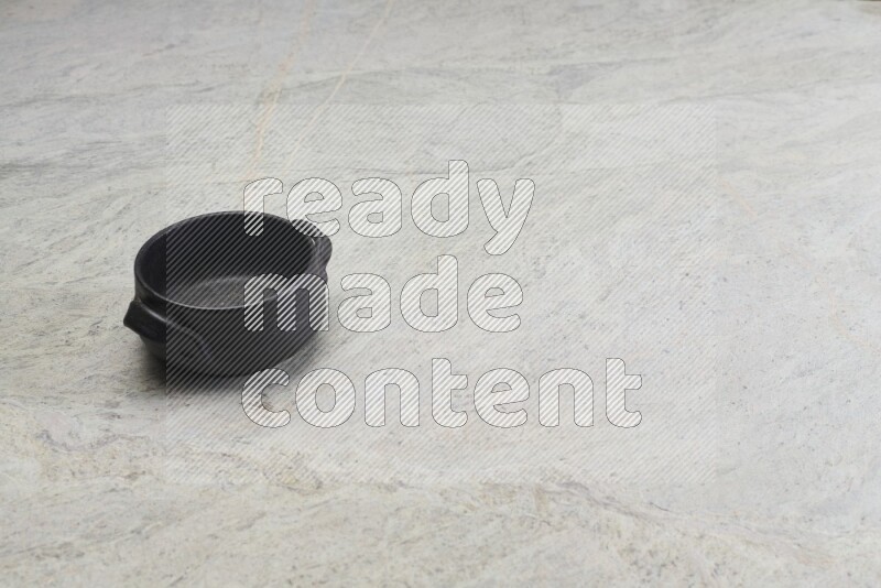 A black pottery bowl on grey marble background