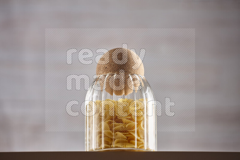 Raw pasta in glass jars on beige background