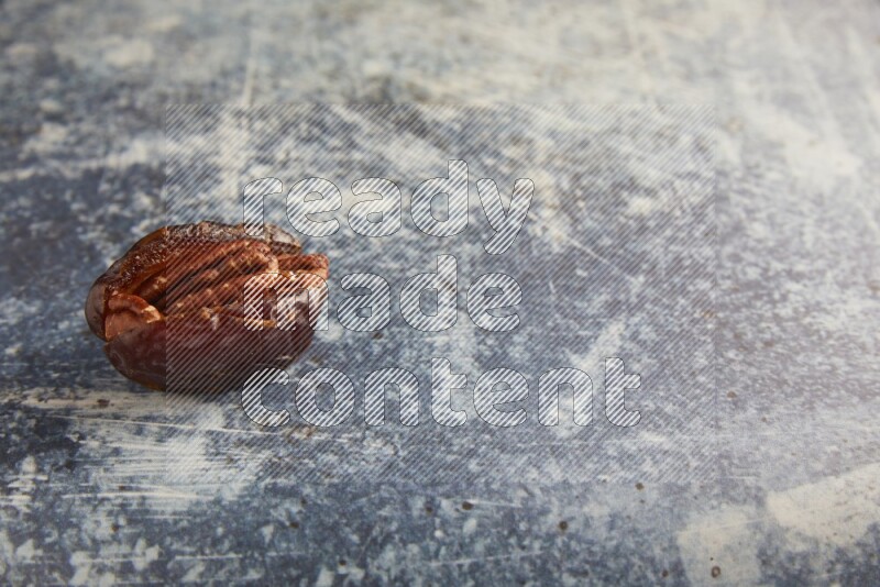 pecan stuffed madjoul date on a rustic blue background