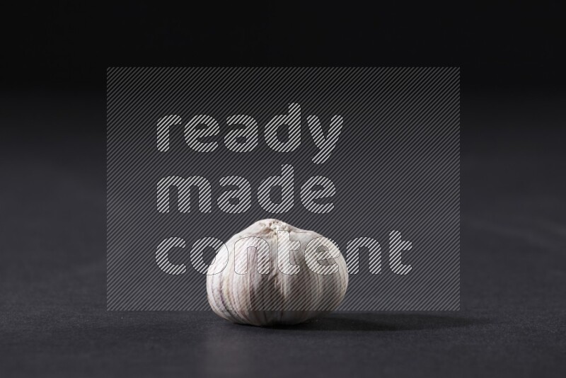 A whole garlic bulb placed on a black flooring