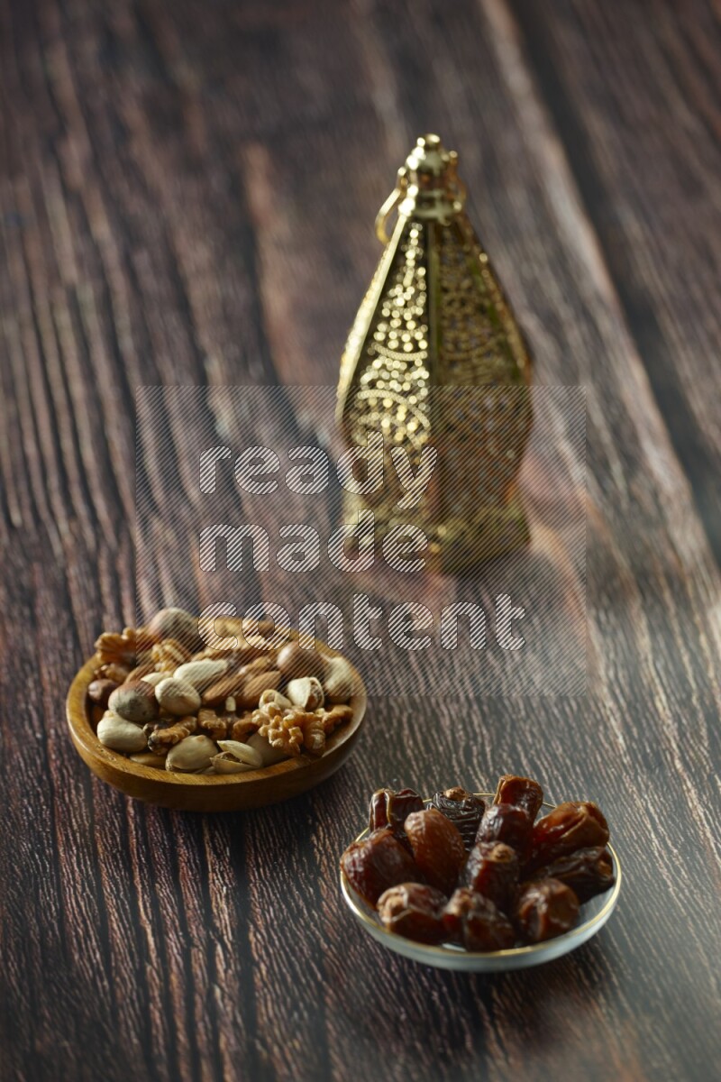 A golden lantern with different drinks, dates, nuts, prayer beads and quran on brown wooden background