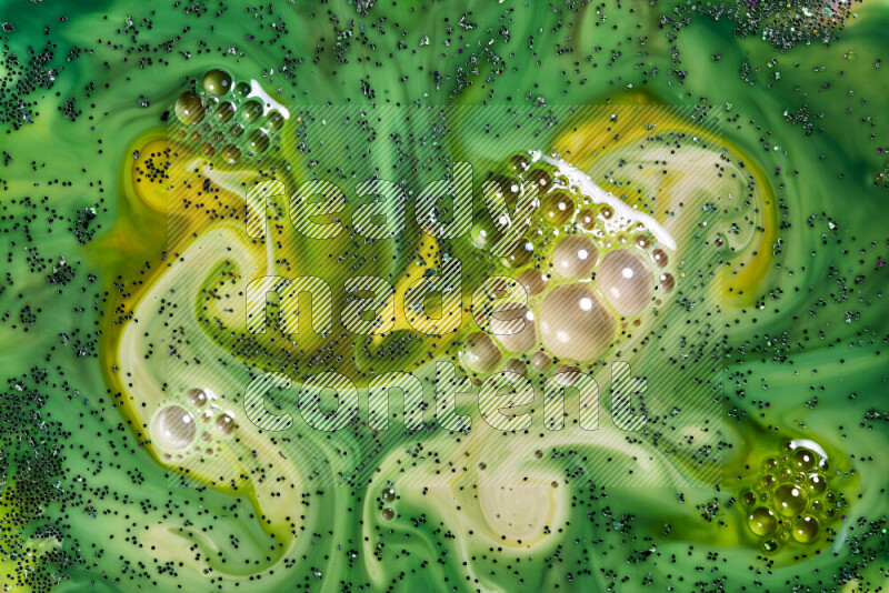 A close-up of sparkling green glitter scattered on swirling yellow and green background