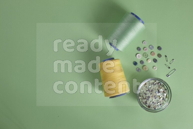A collection of sewing and tailoring tools arranged on a green background