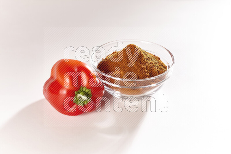 A glass bowl full of ground paprika powder on white background