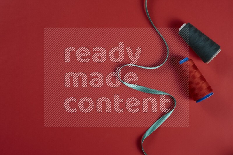 A green and red collection of sewing and tailoring tools arranged on a red background