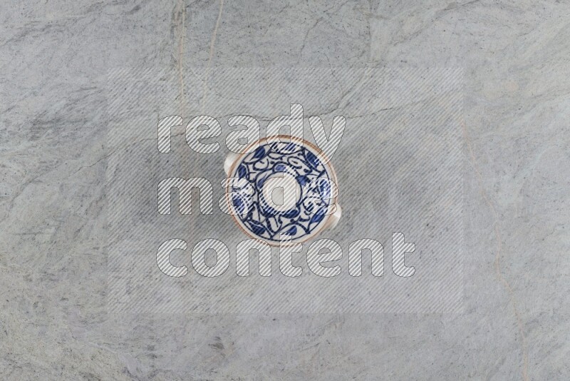 A multicolored pottery pot with its lid on grey marble background