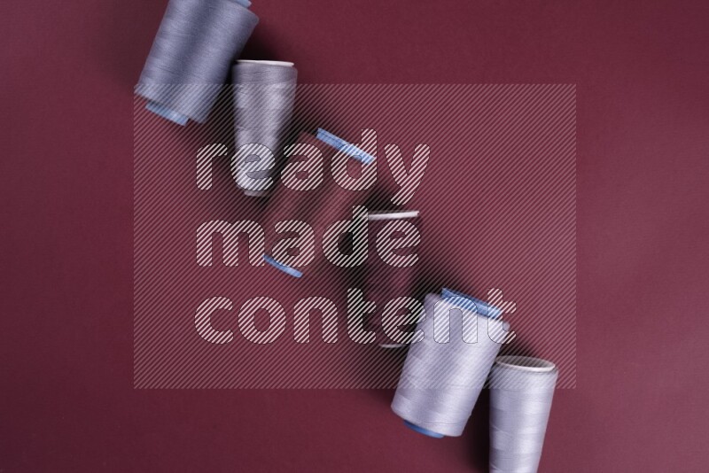 A grey collection of sewing and tailoring tools arranged on a red background