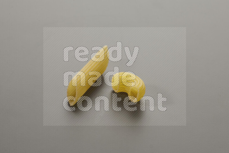 Penne pasta with other types of pasta on grey background