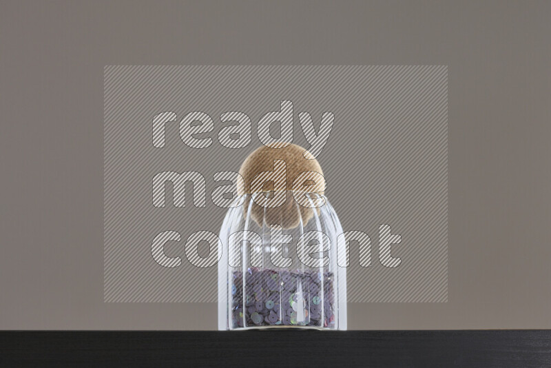 Sequins in a glass jar on black background