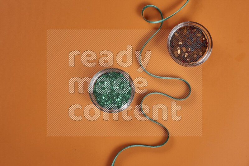 A green and orange collection of sewing and tailoring tools arranged on a orange background
