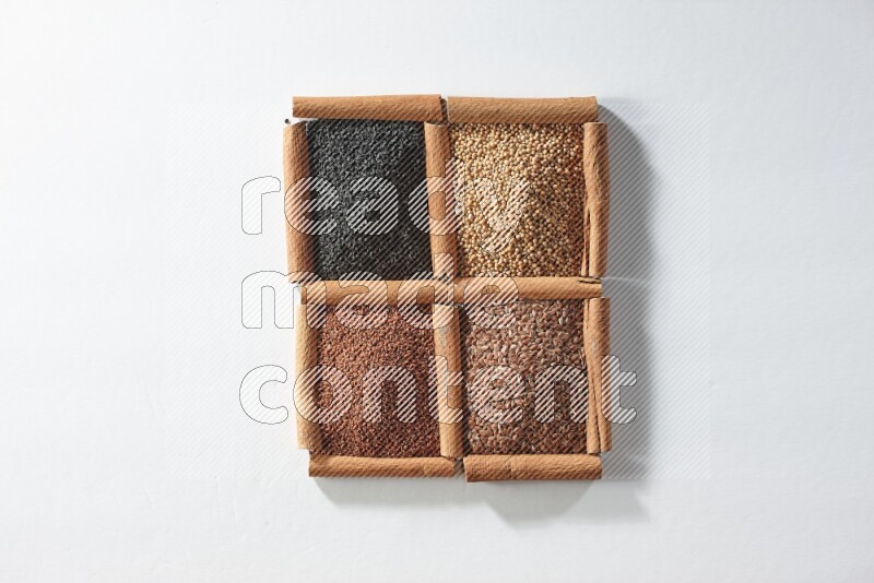 4 squares of cinnamon sticks full of black seeds, mustard seeds, flaxseeds and garden cress on white flooring