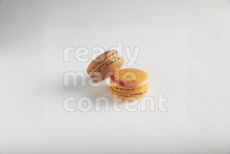 45º Shot of of two assorted Brown Irish Cream, and Orange Exotic macarons on white background