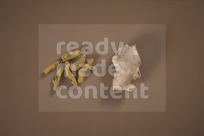 An assorted whole spices including fresh and dried ginger, cinnamon sticks, cardamom, turmeric fingers, cloves, star anise on beige background