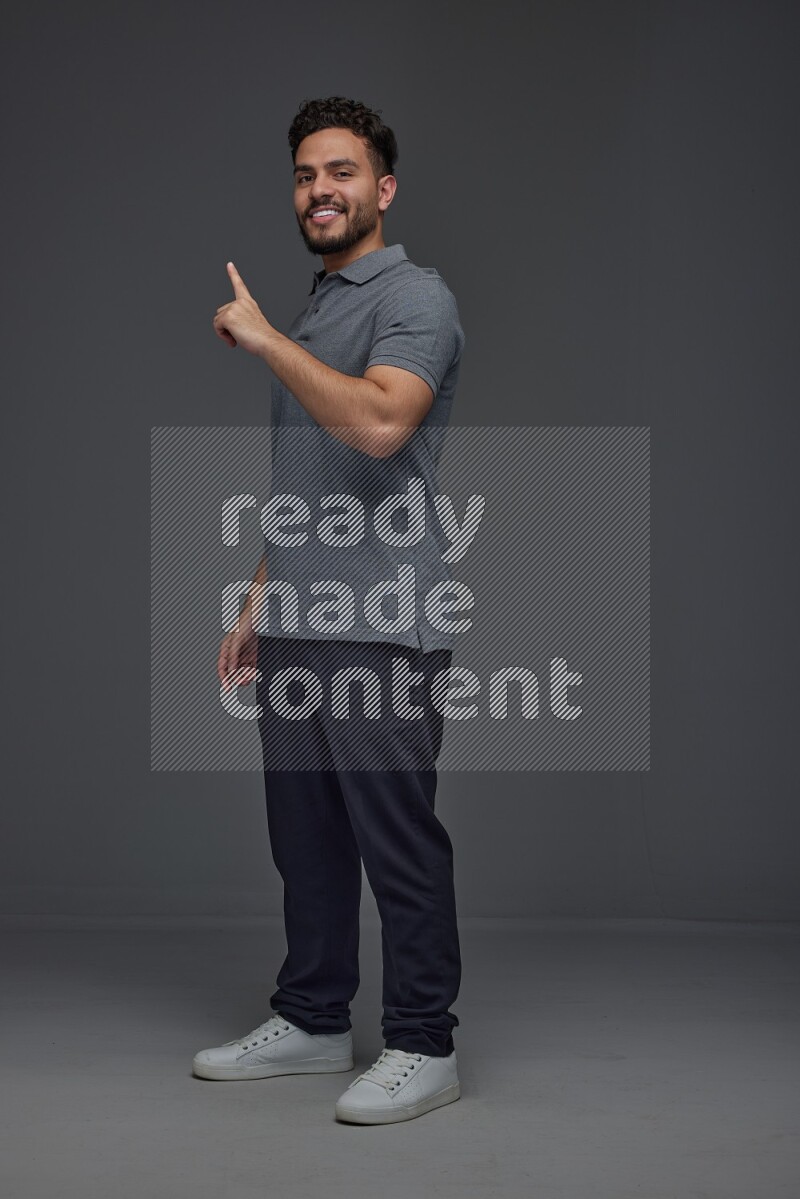 A man wearing casual standing and making multi hand gestures eye level on a gray background