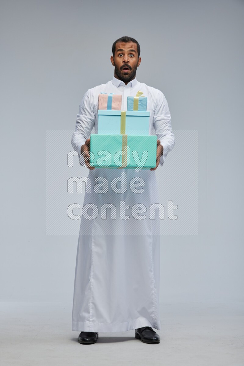 Saudi man Wearing thob standing holding gift box on Gray background