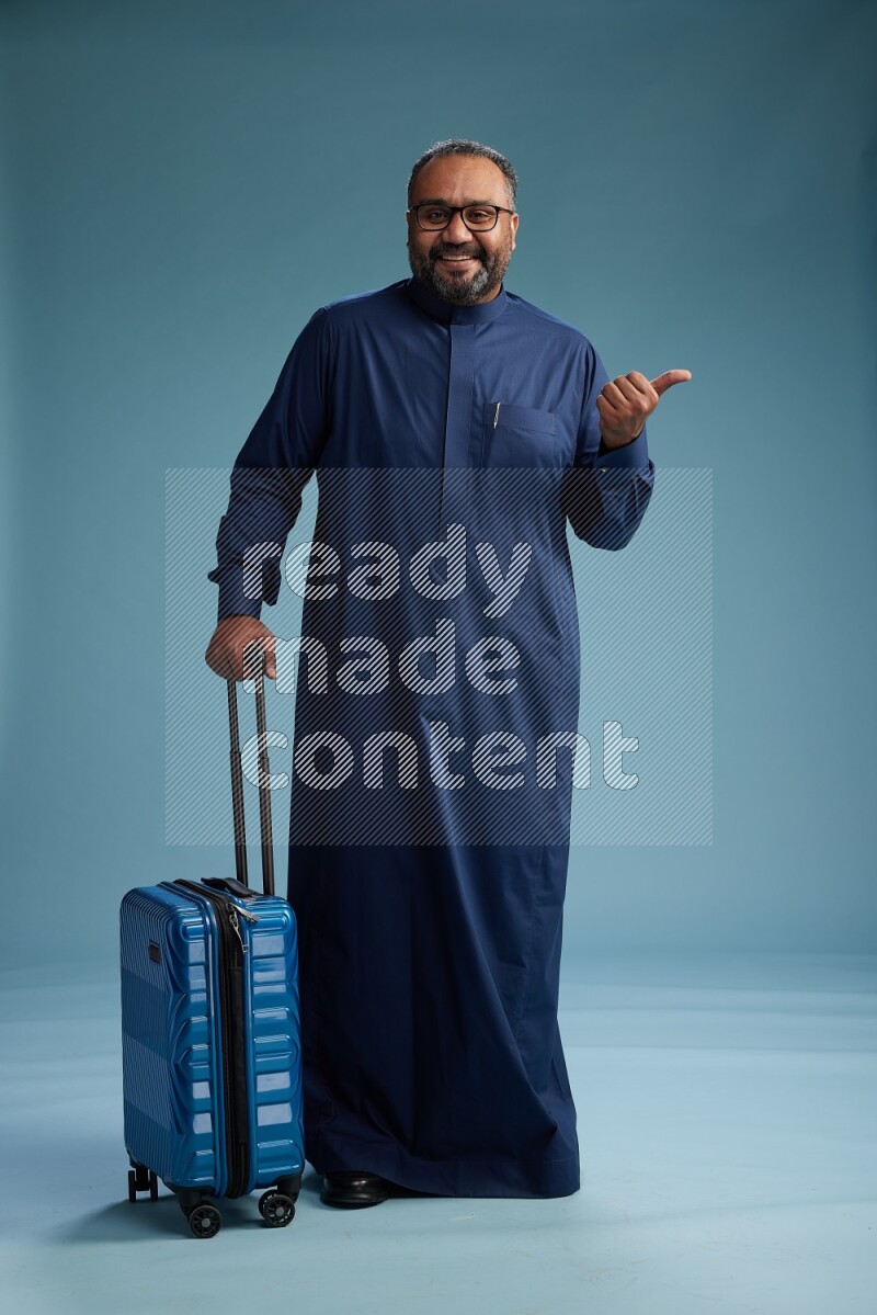 Saudi Man without shimag Standing pulling travel bag on blue background