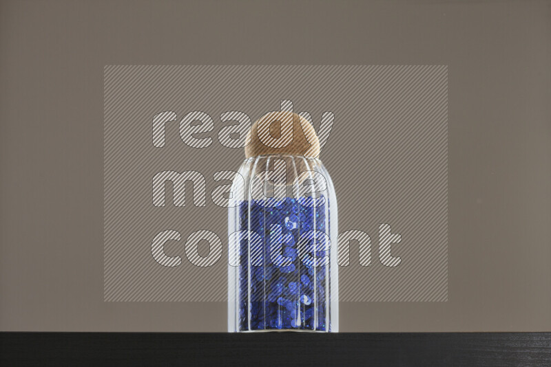 Sequins in a glass jar on black background